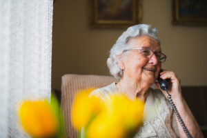 Elderly woman speaks to her daughter and son by telephone